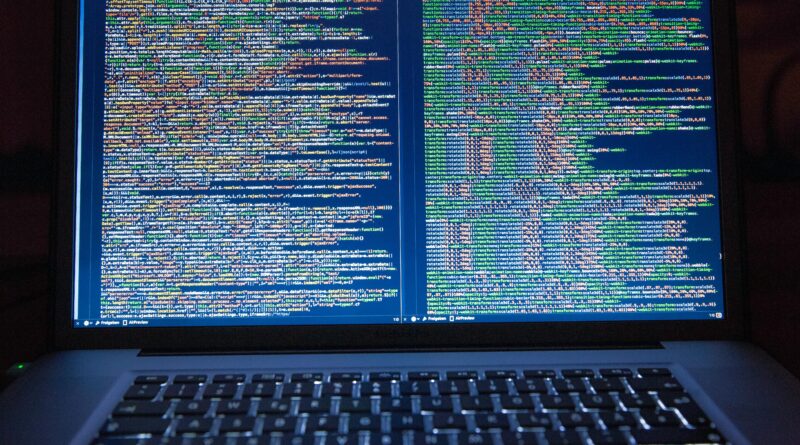 Laptop displaying source code with dual screens for software development.