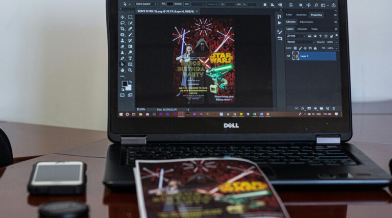 A laptop displaying Star Wars party invitation design in a workspace setting.