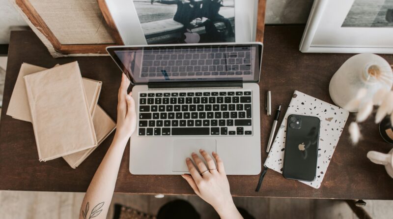 An aesthetic workspace featuring a laptop, smartphone, and stationery items from a top-down view.